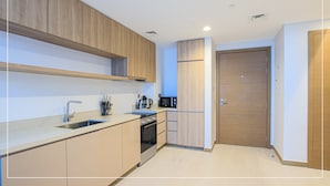 A modern kitchen with wooden cabinets, a stainless steel sink, and a built-in oven. - Spacious 1BR Apt Designed by Missoni (Dubai)
