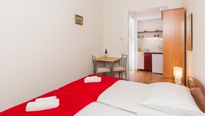 A small hotel room with a bed, a table with chairs, and a kitchenette in the background. - Villa Iveta - Twin Room (Ground Floor) - Martina (Dubrovnik)