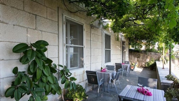 An outdoor patio with stone walls, potted plants, and a table set for two. - Villa Iveta - Twin Room (Ground Floor) - Martina (Dubrovnik)
