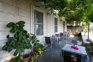 An outdoor patio with stone walls, potted plants, and a table set for two. - Villa Iveta - Twin Room (Ground Floor) - Martina (Dubrovnik)