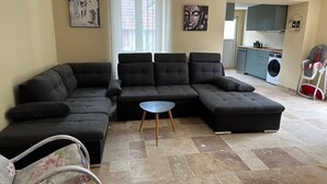 Una sala de estar con un sofá modular, una mesita redonda y un cochecito de bebé.