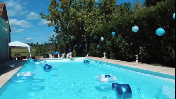 Una piscina con pelotas inflables, una carpa blanca y árboles al fondo.