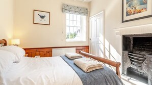 A bedroom with a bed, a window, a fireplace, and a painting on the wall. - Papist Hall Cottages (Barrow upon Humber)