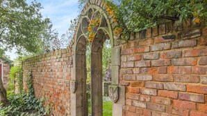 A brick wall with a stone archway and a coat of arms. - Papist Hall Cottages (Barrow upon Humber)