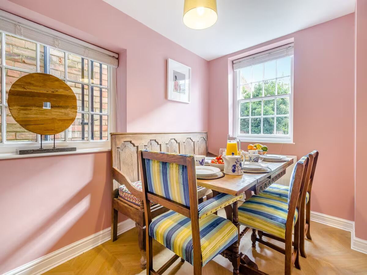 A dining area with a wooden table, striped chairs, and a window with a view of greenery.