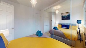 A bedroom with a large bed, a mirror, a door, and a lamp. - Parlaunt House - 3 bedroom with FREE Parking (Langley)