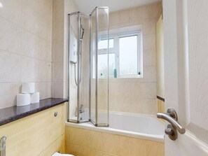 Ein Badezimmer mit Duschkabine aus Glas, einer Badewanne und einem Fenster über der Wanne.