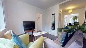 A living room with a flat-screen TV, a small white table, and two sofas with cushions. - Parlaunt House - 3 bedroom with FREE Parking (Langley)