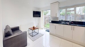 A modern kitchen with white cabinets, a black countertop, and a built-in TV. - Parlaunt House - 3 bedroom with FREE Parking (Langley)
