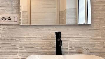 Un bagno moderno con un ampio lavandino ovale, uno specchio e un’illuminazione a incasso.