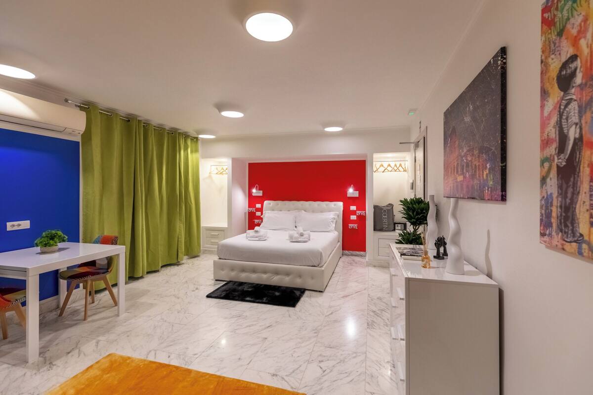 Een moderne slaapkamer met een groot bed, een bureau en een eethoek.