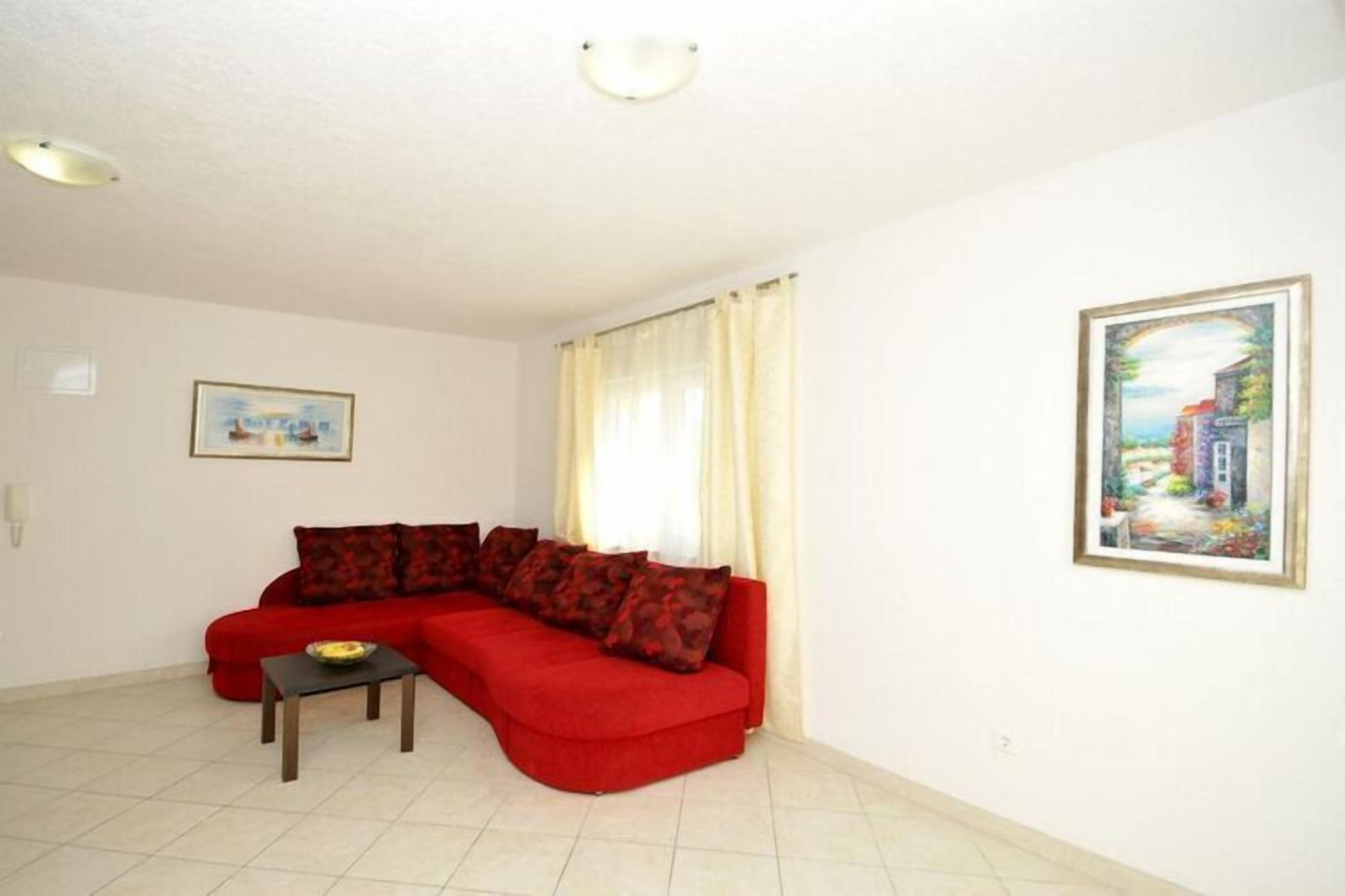 A living room with a red sofa, a small table, and a painting on the wall.