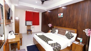 Una camera d'albergo con un letto, una scrivania, una sedia, un armadio e una ventola a soffitto.