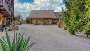 A rustic stone building with a wooden porch and a gravel driveway.
