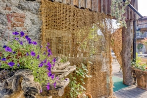 A rustic outdoor area with a wooden fence, a woven net, and purple flowers. - Luxury Glamping House Pia (Ivančna Gorica)