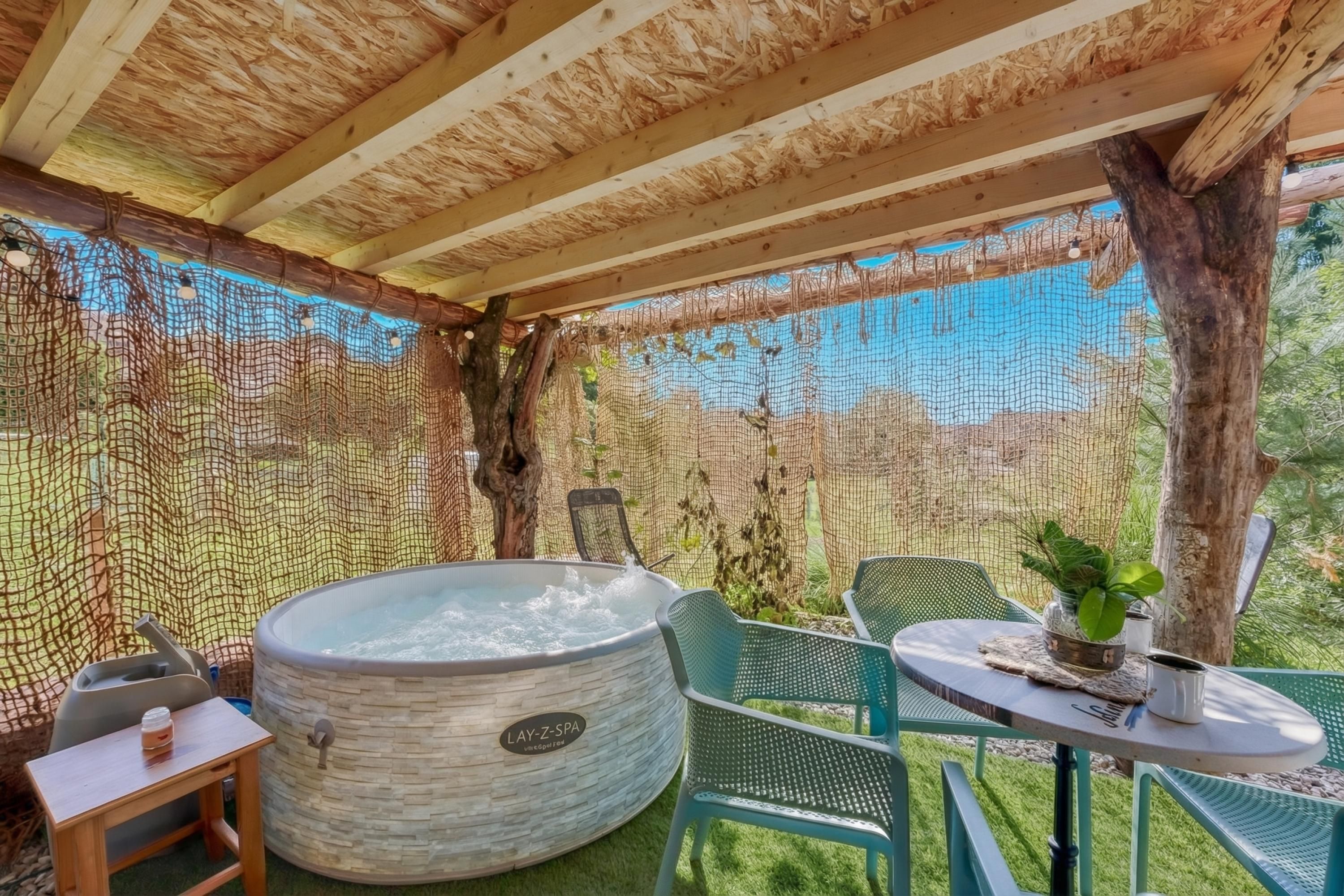 Ein Wellnessbereich mit Whirlpool, Sitzgelegenheiten und einem durch ein Netz geschützten Bereich.
