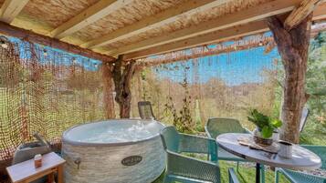 A spa area with a hot tub, seating, and a netted enclosure.