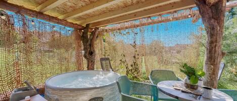 Ein Wellnessbereich mit Whirlpool, Sitzgelegenheiten und einem durch ein Netz geschützten Bereich.