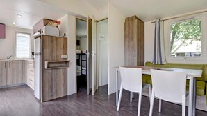 A modern kitchen with a built-in refrigerator, wooden cabinets, and a dining area with a table and chairs. - 6 Person Holiday Park Home in Jelling (Jelling)