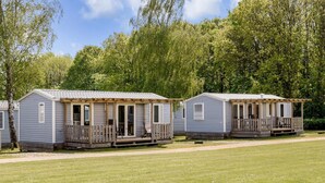 A row of mobile homes with attached porches, set against a backdrop of trees and a clear sky. - 6 Person Holiday Park Home in Jelling (Jelling)