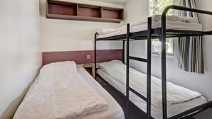 A dormitory room with bunk beds, a window with curtains, and a shelf above the beds. - 6 Person Holiday Park Home in Jelling (Jelling)