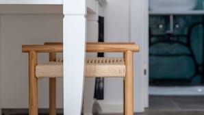 A wooden chair with a woven seat and backrest, positioned in a room with a white column and a green upholstered chair in the background. - Mamma mia luxury rooms - Double Room with Sea View (Relaxing beachfront paradise) - 2 (Trogir)
