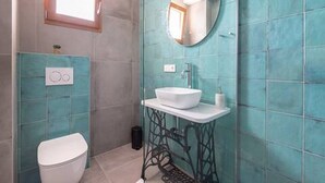A bathroom with teal tiles, a round mirror, a white sink, and a toilet. - Mamma mia luxury rooms - Double Room with Sea View (Relaxing beachfront paradise) - 2 (Trogir)