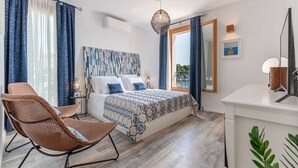 A bedroom with a bed, a chair, a desk, and a window with curtains.