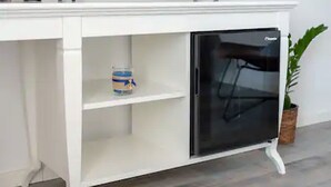 A white cabinet with a black refrigerator and a shelf with a can.