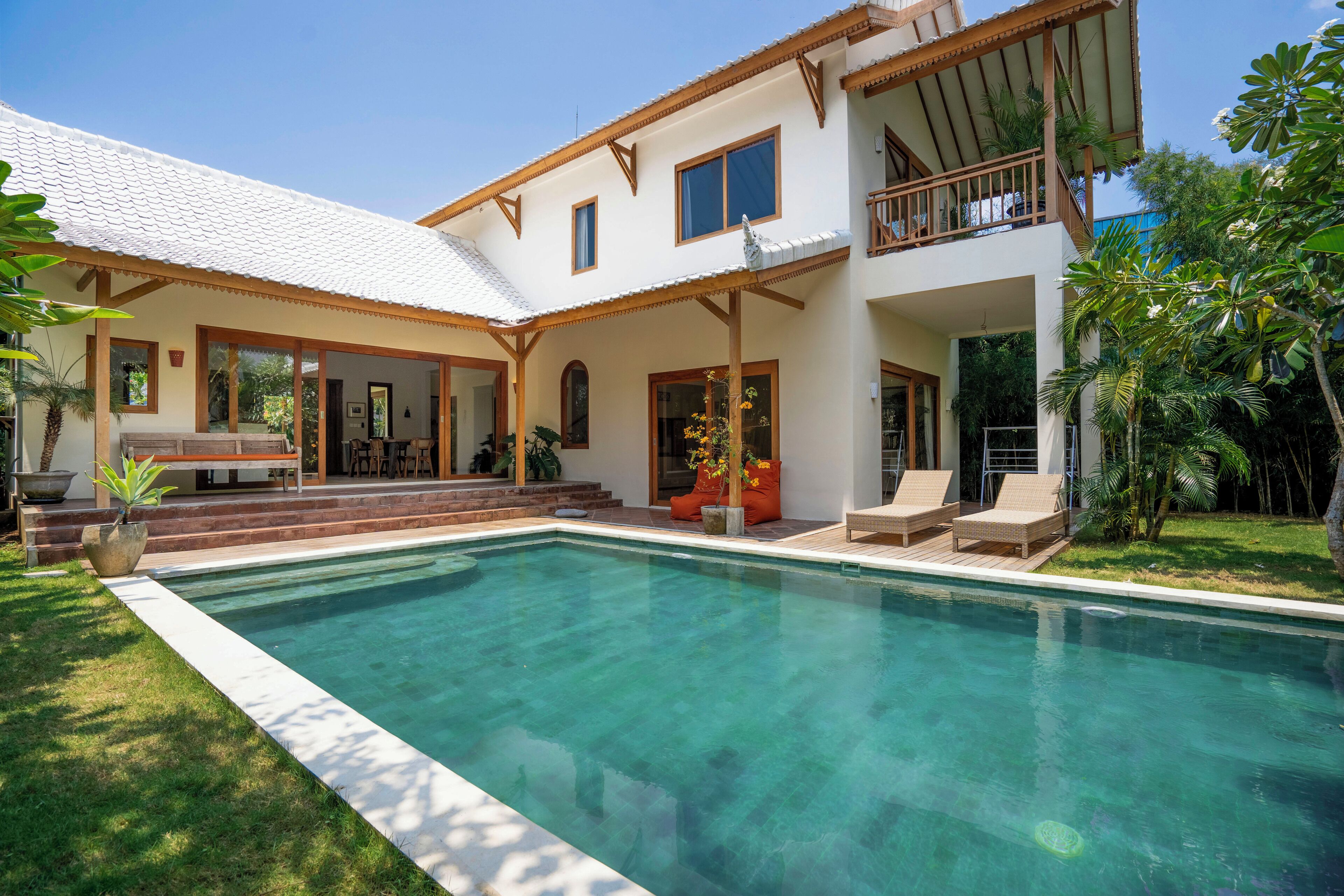 Une maison à deux étages avec une piscine, un patio couvert et un balcon.