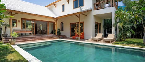 A two-story house with a swimming pool, a covered patio, and a balcony.