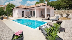 Une maison avec une piscine, un espace salon extérieur et un jardin.