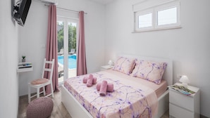 Une chambre à coucher comprenant un lit, un bureau, une chaise, une table de chevet et une fenêtre.