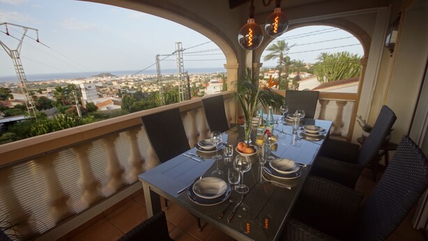 Une table à manger dressée pour quatre personnes, avec vue sur le paysage urbain et les lignes électriques.
