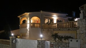 Un bâtiment à deux étages, doté d’une façade en pierre, d’un balcon avec des balustrades et d’une entrée éclairée.