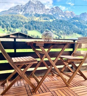A wooden deck with a table and chairs, overlooking a mountainous landscape. - Cosy Chalet With Garden (Rougemont)