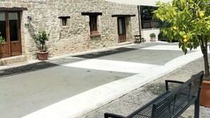 Edifici de pedra amb un pati, una banca i un arbre en test