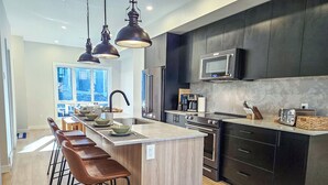 A modern kitchen with a central island, bar stools, a microwave, and a toaster. - Nordix Townhome / Private hot tub / New build (Panorama)
