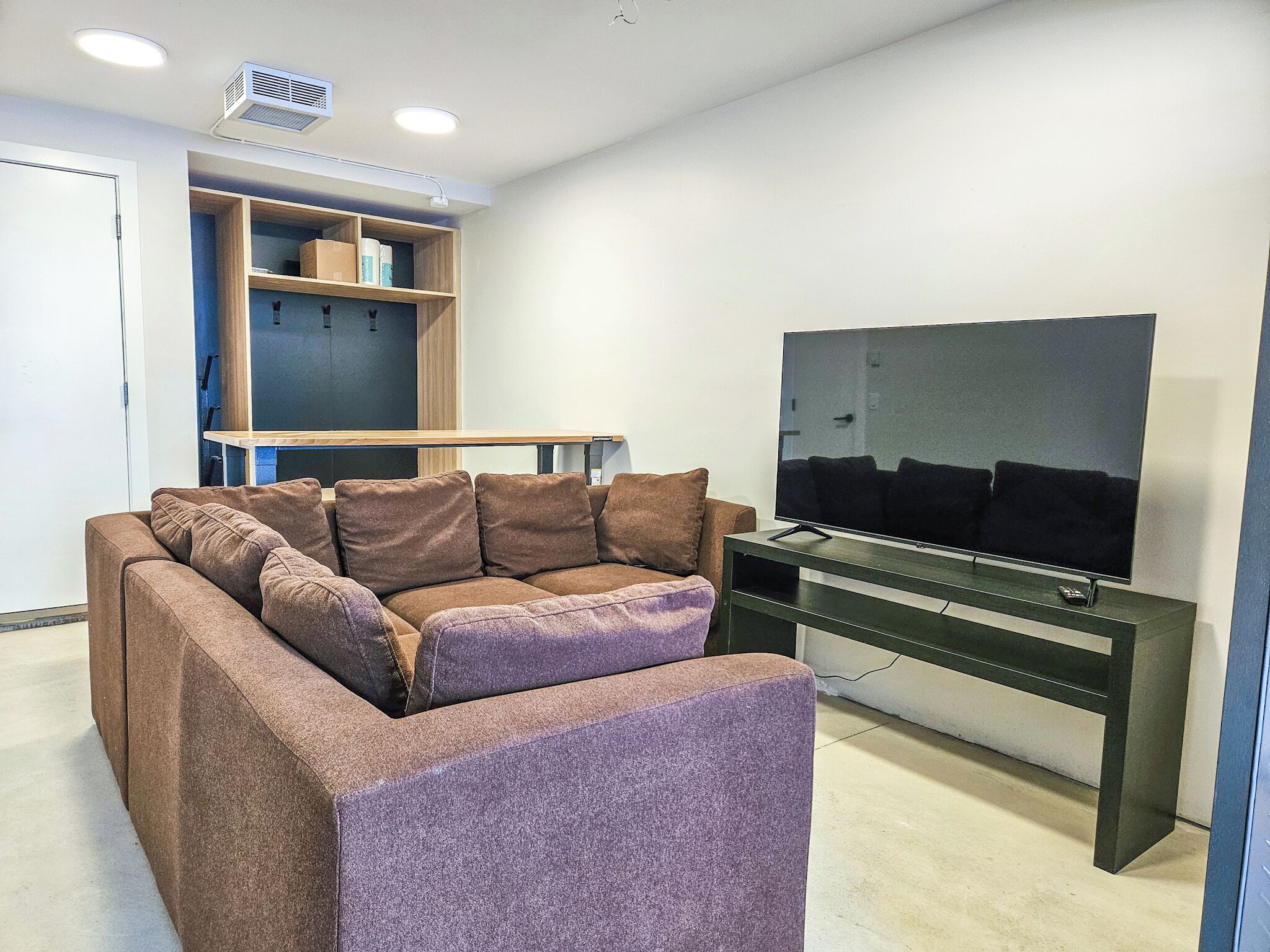 A modern living room with a sectional sofa, a flat-screen TV, and built-in shelving.