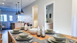 A modern dining area with a wooden table set for four, featuring bowls, plates, and cutlery. - Nordix Townhome / Private hot tub / New build (Panorama)