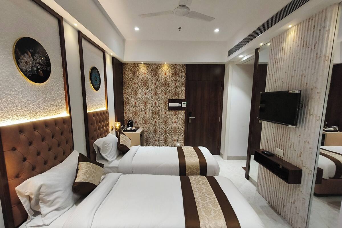 Habitación de hotel con dos camas, televisor, escritorio con lámpara y un adornado en la pared.