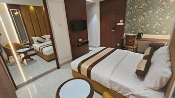 Habitación de hotel con cama, una mesita redonda, una silla, un escritorio con silla, televisor y espejo.