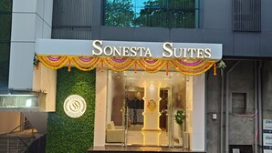 L'entrada de Sonesta Suites amb un disseny modern, incloent una escala que mena a l'entrada, un logotip a la paret i un rètol sobre la porta.