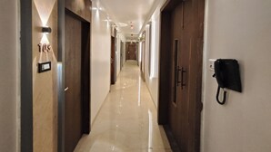 Passadís d'hotel amb terra de marbre, portes de fusta i un telèfon a la paret.