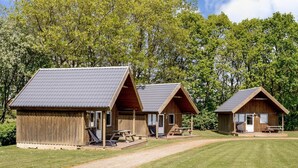 Two wooden cabins with pitched roofs, each featuring a porch and a picnic table. - 4 Person Holiday Park Home in Jelling (Jelling)