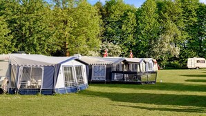 A row of caravans and tents in a grassy field with trees in the background. - 4 Person Holiday Park Home in Jelling (Jelling)