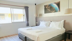 A modern hotel room with a large bed, a view of the city, and a painting on the wall. - Whale Cha-Am (Cha-am)