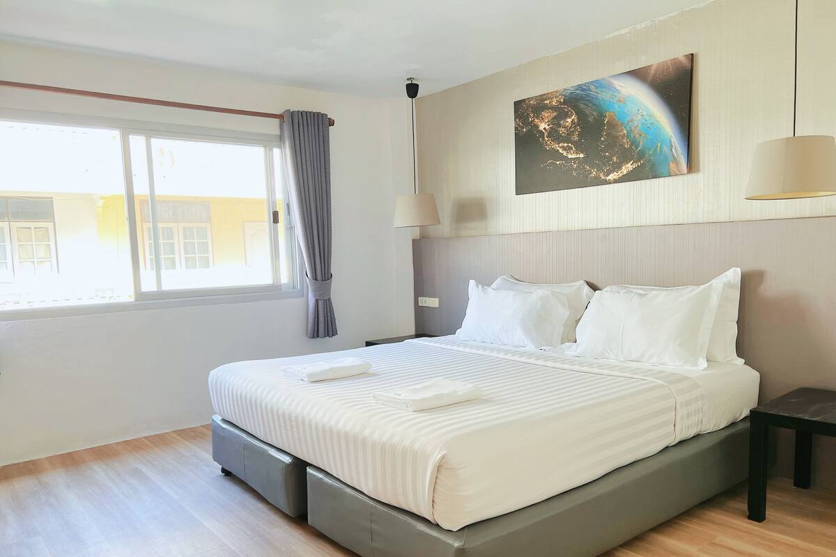 Ein modernes Hotelzimmer mit einem großen Bett, Blick auf die Stadt und einem Gemälde an der Wand.