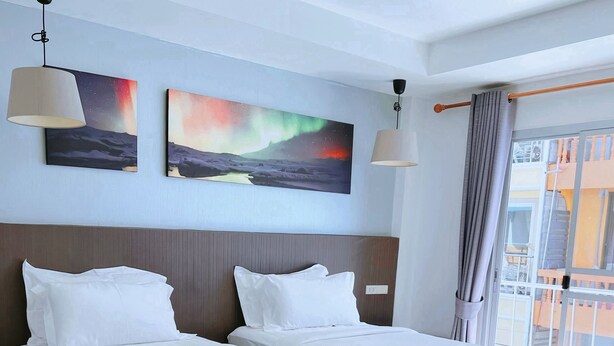 A hotel room with two beds, a wooden floor, and artwork on the walls. - Whale Cha-Am (Cha-am)