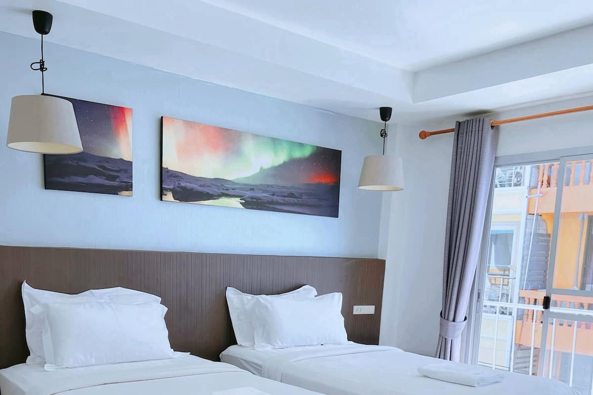 Ein Hotelzimmer mit zwei Betten, Holzboden und Bildern an den Wänden.